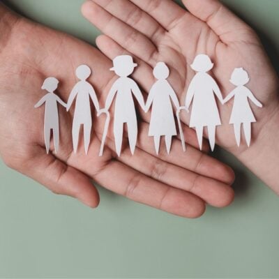 Hands holding paper cutouts of a multigenerational family