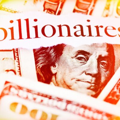 The word 'billionaires' overlaid on close-up U.S. hundred-dollar bills