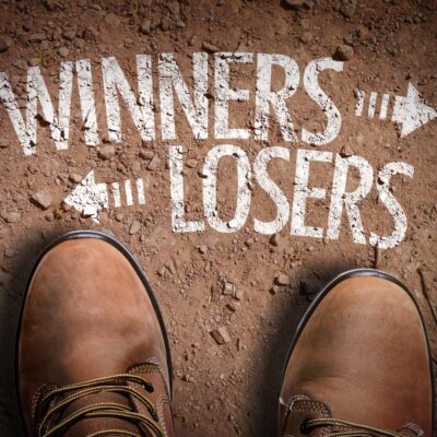 Boots standing on dirt between 'Winners' and 'Losers' directional signs