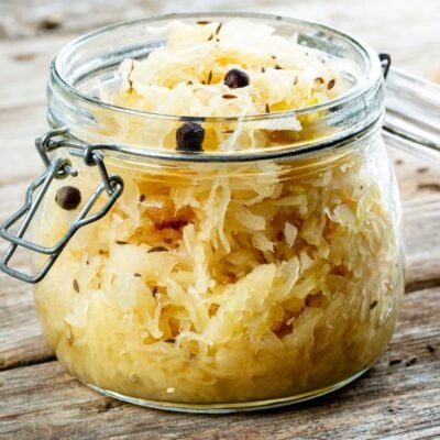 Glass jar filled with sauerkraut and spices on a wooden table