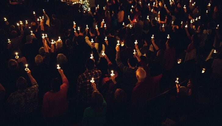 A large group of people holding candles during an event, symbolizing carols sung by candlelight in Australia