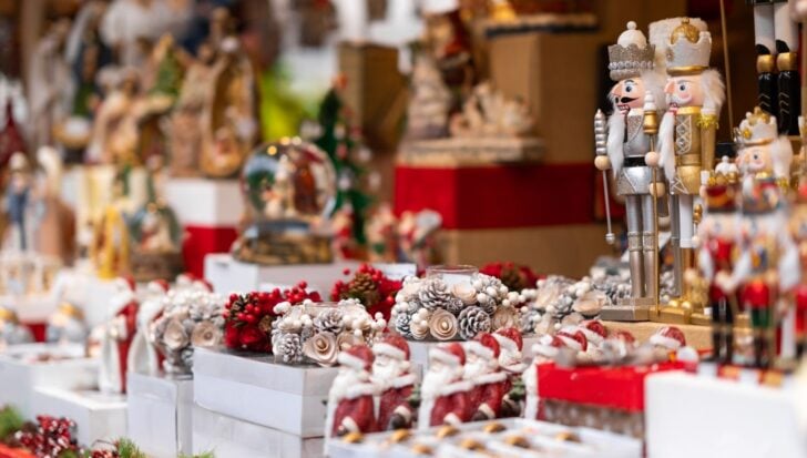 A display of festive Christmas items including nutcracker figures, decorative wreaths with pinecones and berries, and Santa Claus figurines, 