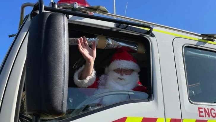 Santa Claus waving from a firetruck window, 