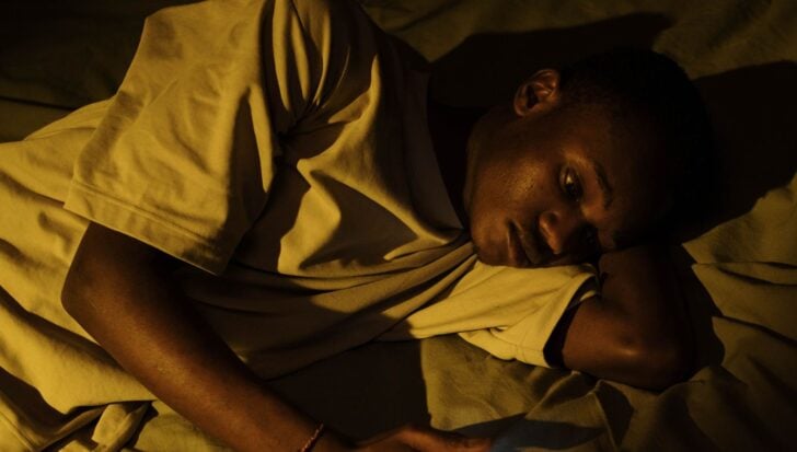 Person lying in bed with a distressed expression