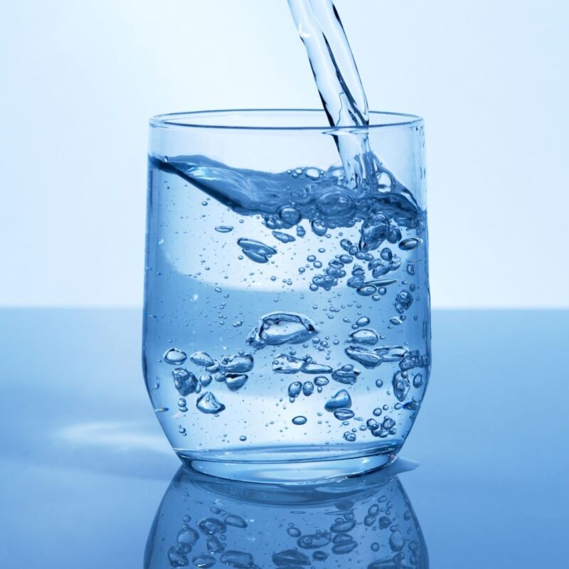 Water being poured into a clear glass with bubbles forming