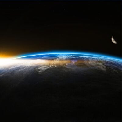 Sunrise over Earth's horizon with visible atmosphere and distant moon