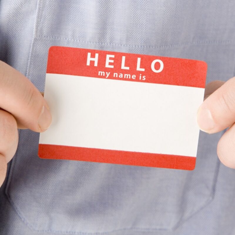 Person holding a blank red and white name tag sticker