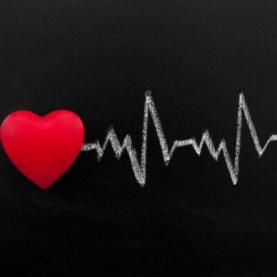 Red heart with white chalk heartbeat line on black background