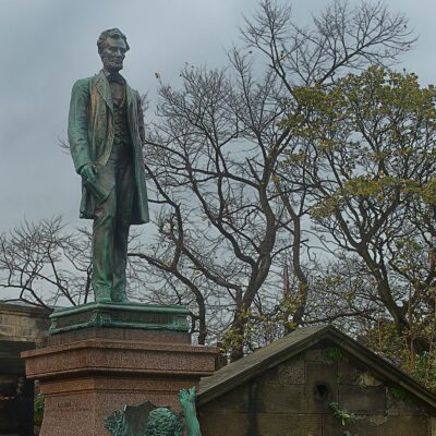 Statue of Abraham Lincoln on a stone pedestal with trees in the background