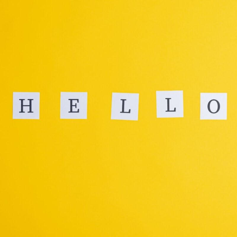 The word HELLO spelled out on white cards against a yellow background