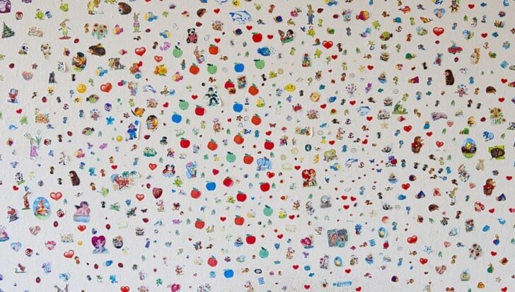 A large assortment of colorful stickers covering a wall, featuring various designs like hearts, animals, and cartoon characters