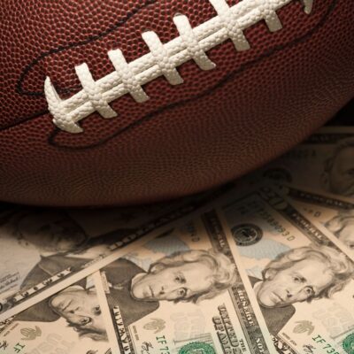 Close-up of a football resting on scattered twenty-dollar bills