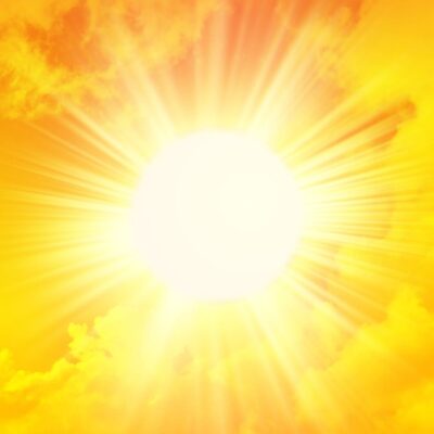 Bright sun shining with intense rays and orange-yellow clouds