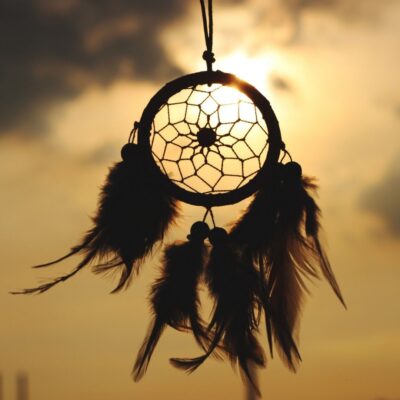 Feathered dreamcatcher hanging against a sunset sky
