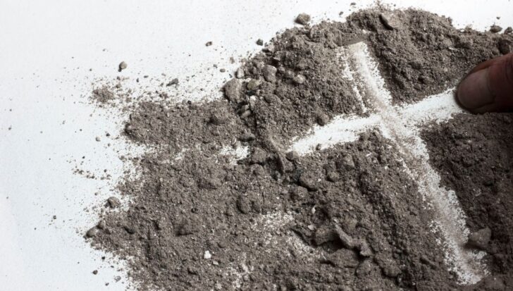 A cross drawn in ashes on a white surface, symbolizing the Day of Ashes, part of Ash Wednesday traditions