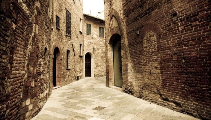 Narrow medieval street with brick buildings and arched doorways