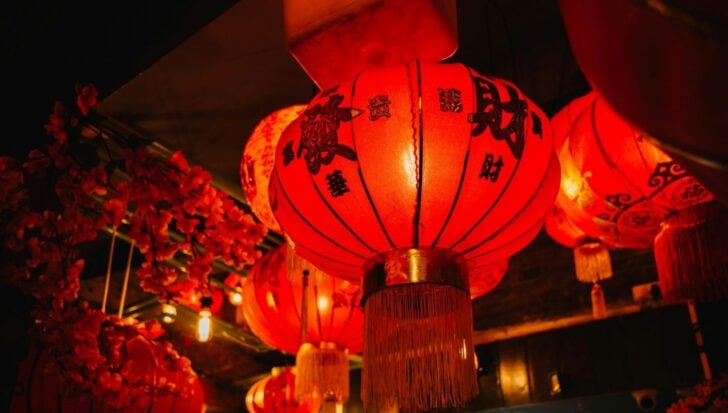 Red Chinese lanterns with black writing hang amidst decorative elements
