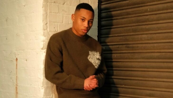 Cruz Lee-Ojo standing against a textured wall, wearing a dark sweater