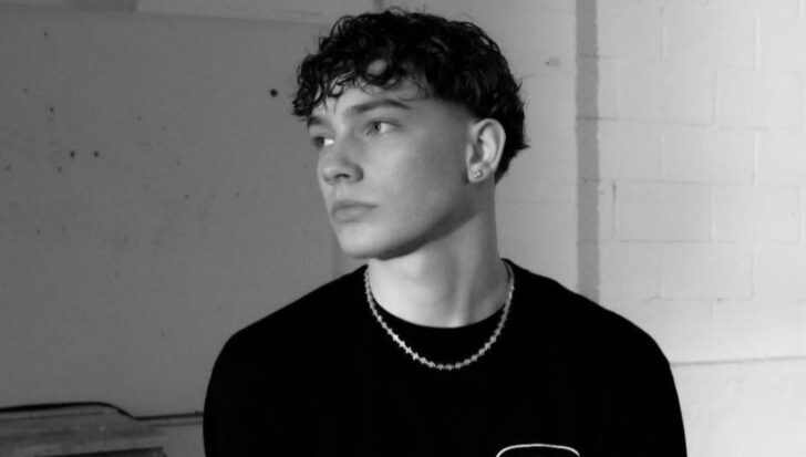 Josh Olliver in a black and white setting with a serious expression wearing a necklace