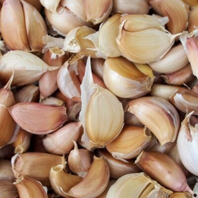 Close-up of peeled garlic cloves with papery skins clustered together