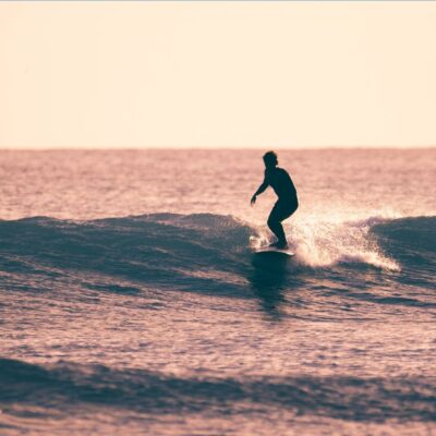 Surfer riding a small wave at sunset