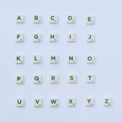 Scrabble letter tiles with green letters laid out in a grid on a light background