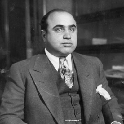 Al Capone with slicked hair in a suit, vest, and patterned tie