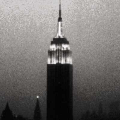 Empire State Building lit at night against a dark New York skyline