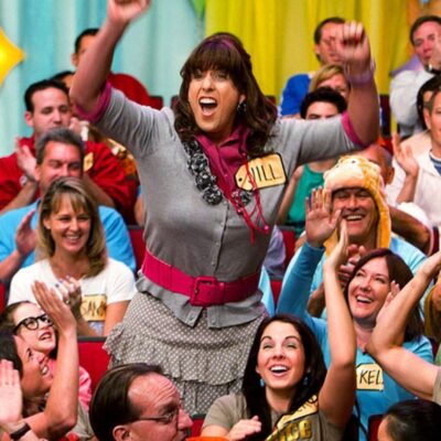 Jill wearing a gray cardigan, a pink belt, and a polka-dot skirt with name tag