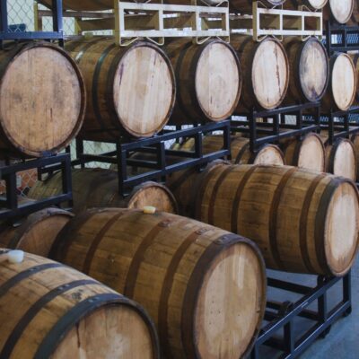 Rows of wooden bourbon barrels stored on metal racks in a warehouse