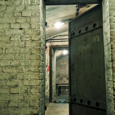 Partially opened heavy metal bunker door in a dim brick-walled underground corridor