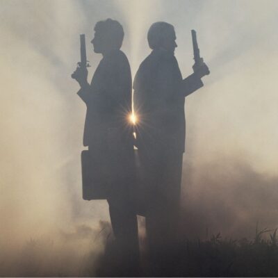 Two silhouetted figures back-to-back, each holding a pistol, amid fog with a sunburst between them