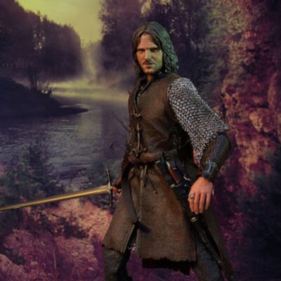 Aragorn in a brown tunic and chainmail with a sword stands in a forest