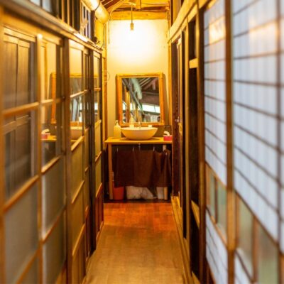 Narrow corridor of a traditional Japanese inn with a sink and mirror at the end