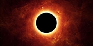 A black hole with a glowing orange-red accretion disc surrounded by dust and gas