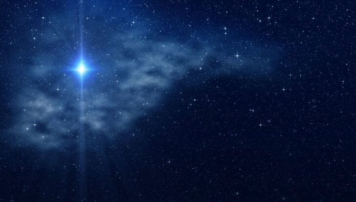 Starry night sky with a bright glowing star surrounded by clouds