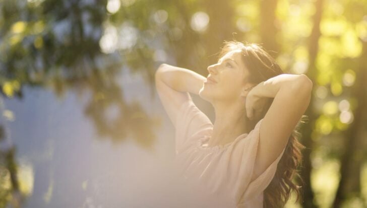 A woman enjoying sunlight among trees