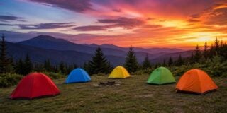Colorful tents set up in a scenic mountain landscape at sunset with vibrant sky and distant peaks