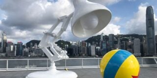 Large model of Pixar's Luxo Lamp and a ball with a star in front of a city skyline