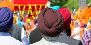 Group of people wearing colorful turbans participating in a Sikh event with bright decorations