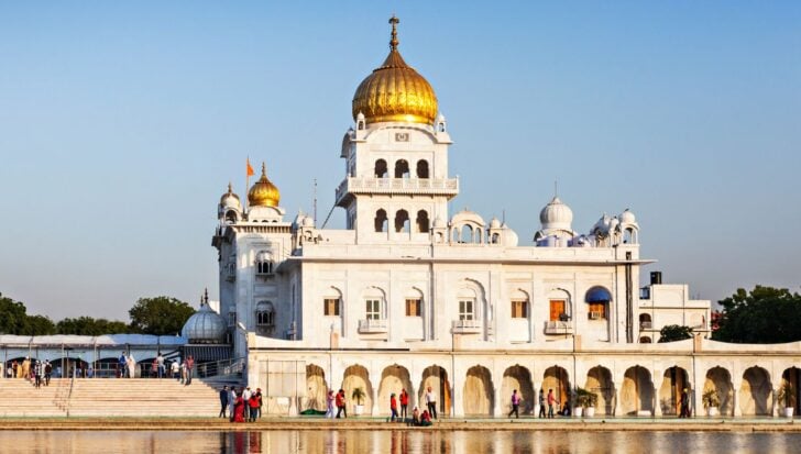 A Sikh temple with golden domes and people gathered around it
